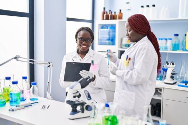 African american women scientist holding test tube writing on document at laboratory