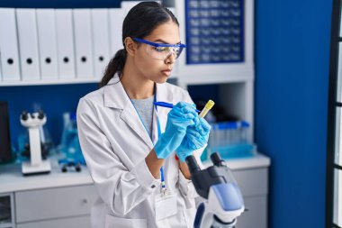 Genç Afrikalı Amerikalı kadın bilim adamı laboratuarda test tüpüne yazdı.