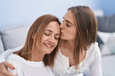 Two women mother and daughter hugging each other at home