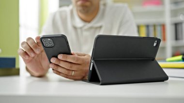 Genç İspanyol öğrenci kütüphane üniversitesinde dokunmatik ve akıllı telefon kullanıyor.