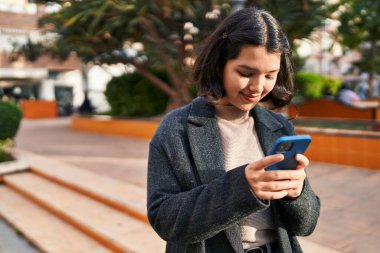 Parkta akıllı telefon kullanan kendine güvenen genç bir kadın.