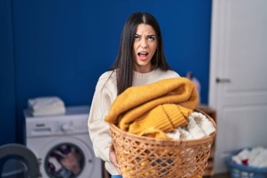 Çamaşır sepetini tutan genç kadın kızgın ve kızgın çığlık atıyor sinirli ve öfkeliydi, öfkeyle bağırıyordu.. 