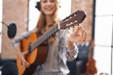 Genç sarışın müzisyen müzik stüdyosunda klasik gitar çalıyor.