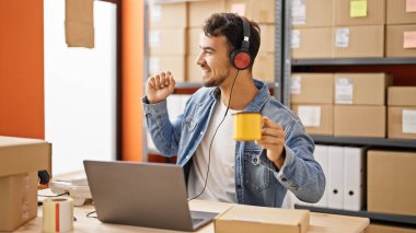 Latin kökenli genç bir iş adamı ofiste kahve içerek müzik dinliyor.