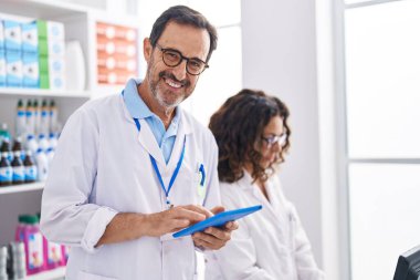 Eczanede dokunmatik ped ve bilgisayar kullanan kadın ve erkek eczacılar.