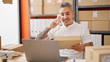 İspanyol asıllı genç iş adamı ofiste telefon paketinden konuşuyor.