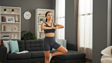 Genç ve güzel İspanyol kadın evde yoga egzersizi yapıyor.