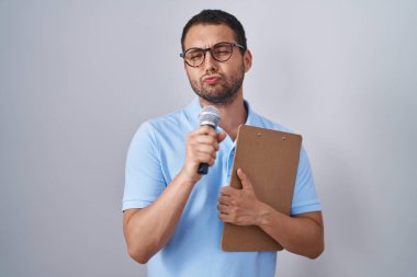 Latin asıllı adam elinde mikrofon ve pano ile kameraya bakıp öpüşüyor ve çok seksi oluyor. aşk ifadesi. 