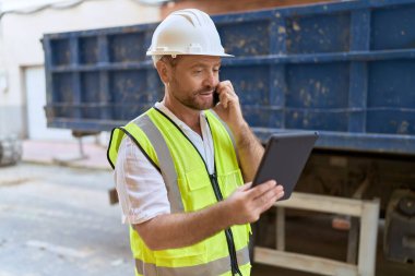 Middle age man architect talking on smartphone using touchpad at street