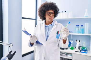 African american woman scientist reading report holding test tube at laboratory