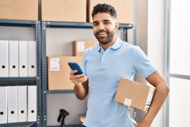 Genç bir İspanyol iş adamı ofiste akıllı telefon paketi kullanıyor.