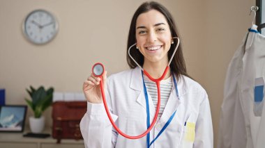 Klinikte steteskop tutan güzel, İspanyol bir doktor gülümsüyor.