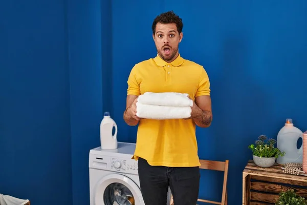 Ung Latinamerikansk Man Som Håller Rena Handdukar Tvättstugan Chockansikte Ser — Stockfoto