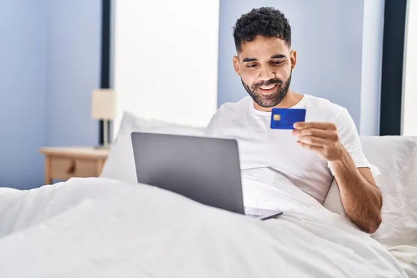 Молодий Іспаномовний Чоловік Використовує Ноутбук Кредитну Картку Сидячи Ліжку Спальні — стокове фото