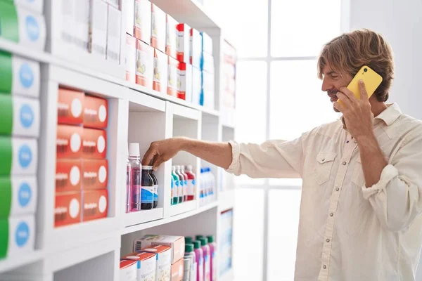 Молодой Человек Клиент Разговаривает Смартфоне Держа Бутылку Лекарством Аптеке — стоковое фото