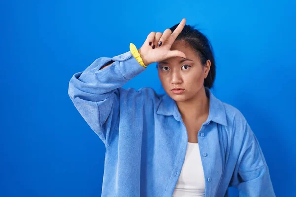 Азиатская Молодая Женщина Стоящая Синем Фоне Высмеивает Людей Пальцами Лбу — стоковое фото