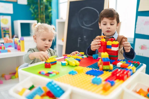 stock image Adorable boy and girl playing with construction blocks sitting on table at kindergarten