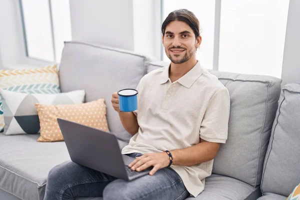 Young Hispanic Man Using Laptop Drinking Coffee Sitting Sofa Home — Stock Photo, Image