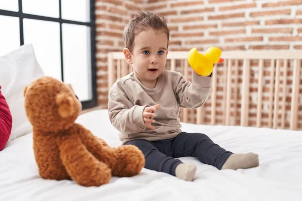 可爱的惊慌失措的男孩抱着鸭玩具坐在卧室的床上 — 图库照片