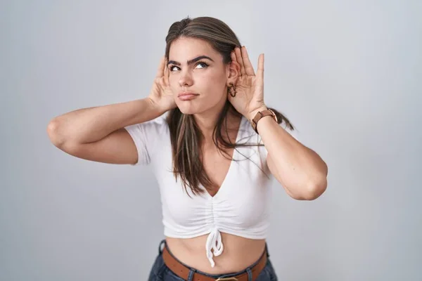 Joven Hermosa Mujer Con Camiseta Blanca Casual Tratando Escuchar Ambas —  Fotos de Stock