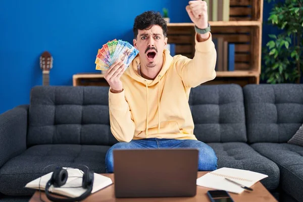Homem Hispânico Trabalhando Com Laptop Segurando Notas Francos Suíços Irritado — Fotografia de Stock