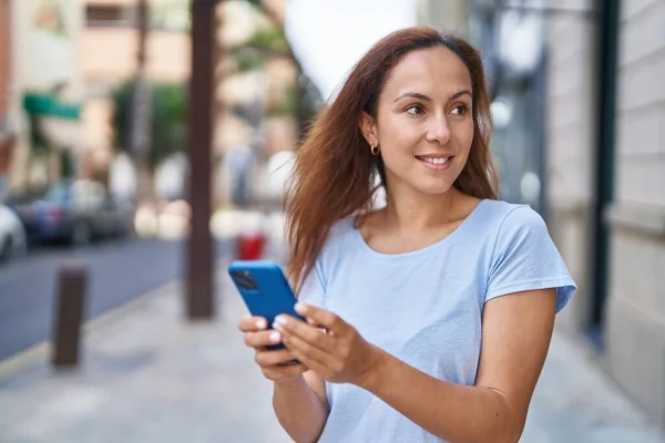 若い女性は路上でスマートフォンを使って自信を持って笑顔 — ストック写真