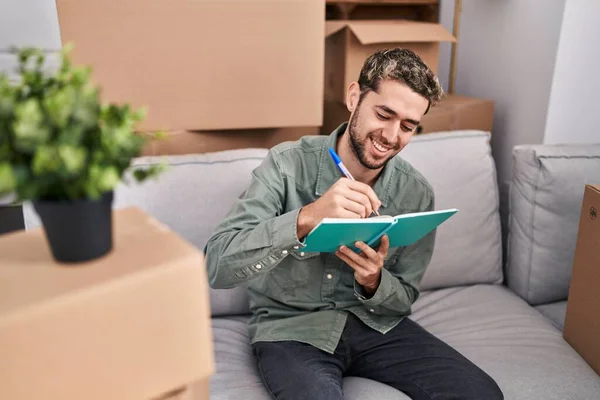 Young Man Writing Notebook Sitting Sofa New Home — Foto Stock