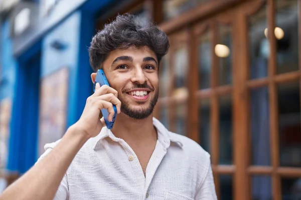 若いアラブ人の男は路上でスマートフォンで自信を持って話して笑顔 — ストック写真