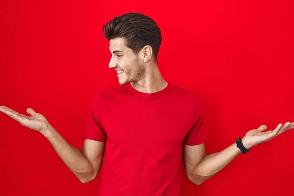 Jonge Spaanse Man Staat Rode Achtergrond Glimlachend Met Beide Handen — Stockfoto