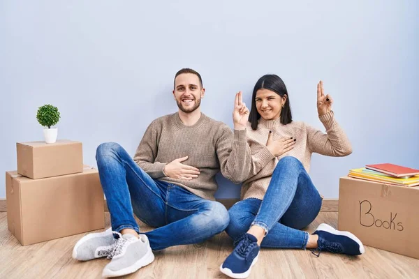 Young Couple Moving New Home Smiling Swearing Hand Chest Fingers — Stock Photo, Image