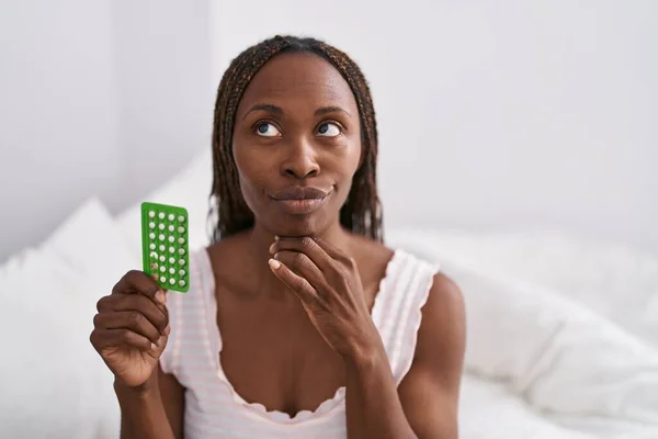 Mujer Afroamericana Sosteniendo Píldoras Anticonceptivas Cara Seria Pensando Pregunta Con —  Fotos de Stock