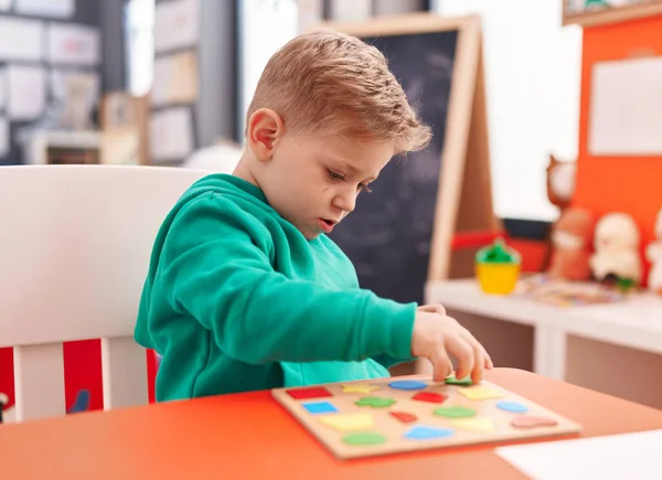 可愛いですCaucasian男の子遊びとともに数学パズルゲーム上のテーブルの上に座って幼稚園 — ストック写真