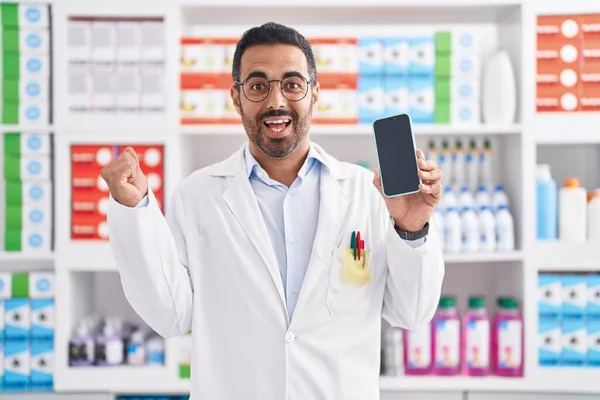 Латиноамериканец Бородой Работающий Аптеке Показывает Экран Смартфона Кричащий Гордостью Празднующий — стоковое фото