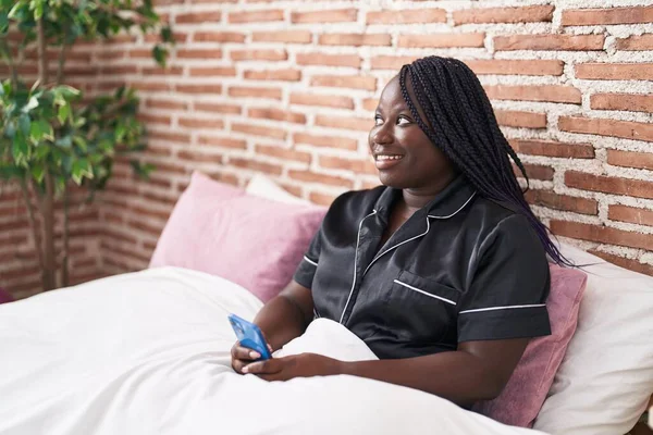 Afrikkalainen Amerikkalainen Nainen Käyttää Älypuhelinta Istuu Sängyssä Makuuhuoneessa — kuvapankkivalokuva