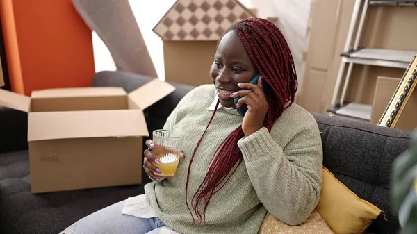 在新家 头发辫子的非洲女人自信地在智能手机上说话 — 图库照片