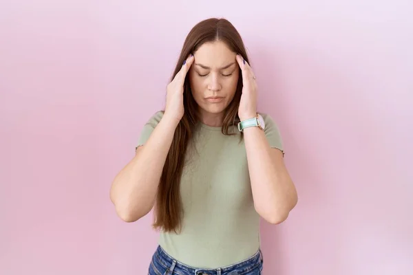 ストレスのために頭の上に手でピンクの背景に立って美しいブルネットの女性 片頭痛 — ストック写真
