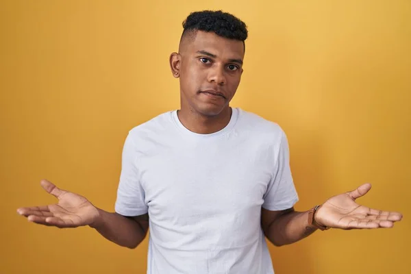 Junger Hispanischer Mann Steht Ratlos Vor Gelbem Hintergrund Und Verwirrt — Stockfoto