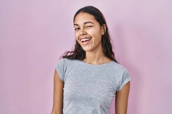 Junge Brasilianerin Lässigem Shirt Vor Rosa Hintergrund Zwinkert Die Kamera — Stockfoto