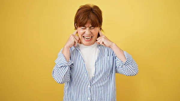 中年女性カバー耳のためのノイズ上の隔離された黄色の背景 — ストック写真