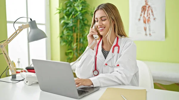 年轻的金发女医生在诊所用手提电脑打电话 — 图库照片