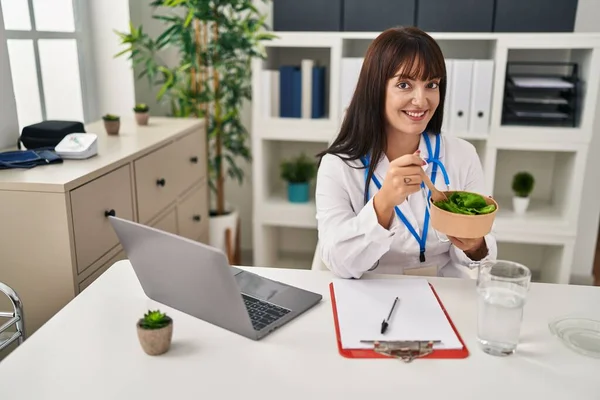 Jovem Bela Mulher Hispânica Médico Usando Laptop Comendo Salada Clínica — Fotografia de Stock