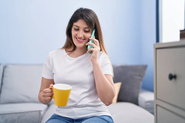 Young Hispanic Woman Drinking Coffee Talking Smartphone Home — Stok fotoğraf