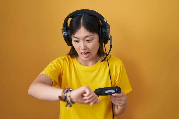 中国的年轻女子玩电子游戏时拿着控制器看着手表时间焦急 生怕迟到 — 图库照片