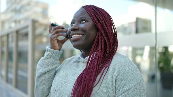 髪の毛を編んだアフリカ人女性が通りでスマートフォンで音声メッセージを聞く — ストック写真