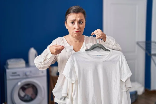 Middle Age Hispanic Woman Holding Shirt Hanger Detergent Powder Depressed — Stock Photo, Image