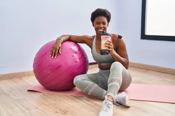 Afrikansk Amerikansk Kvinna Dricker Smoothie Sittandes Yogamattan Sportcentret — Stockfoto