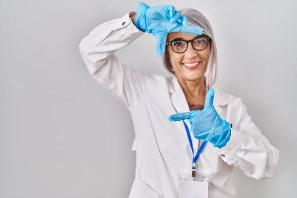 白髪の中年女性は科学者のローブを着て 幸せな顔で手や指でフレームを作り笑顔 創造性と写真の概念 — ストック写真