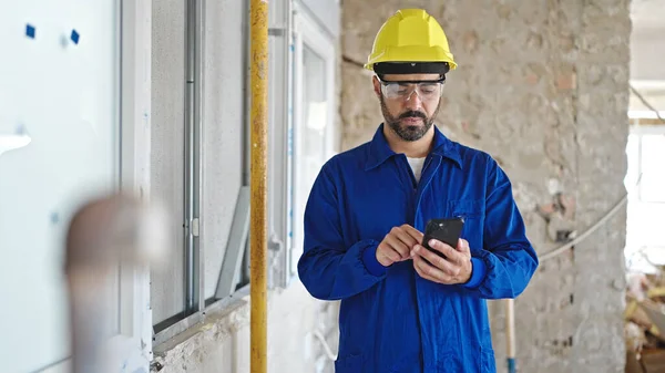 Ung Latinamerikansk Man Arbetare Bär Hatt Med Hjälp Smartphone Byggarbetsplatsen — Stockfoto
