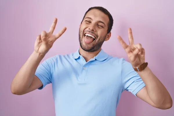 Hispánec Který Stojí Nad Růžovým Pozadím Usmívá Vyplazeným Jazykem Ukazujícími — Stock fotografie