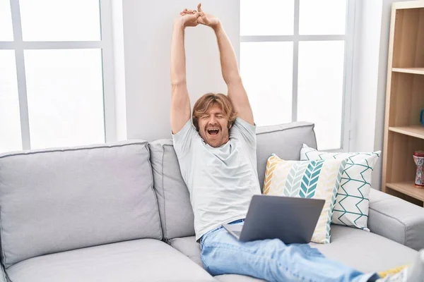 Genç Adam Dizüstü Bilgisayar Kullanıyor Kollarını Açıp Evde Esniyor — Stok fotoğraf